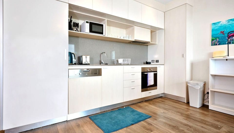 A streamlined, all-white kitchen equipped with integrated appliances and clever storage solutions