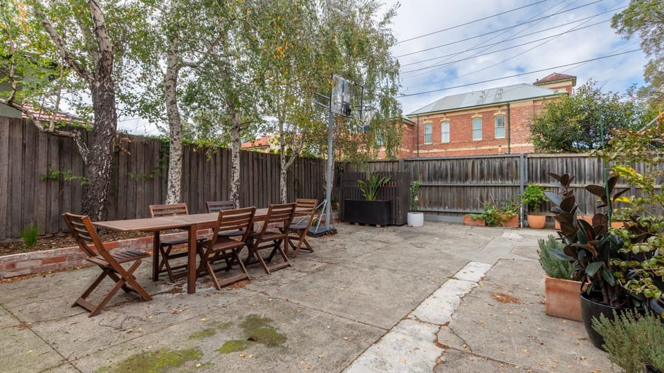 Shared spacious outdoor courtyard area with dining setting and leafy surrounds