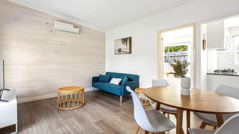 This wide angle showcases the fluid, airy transition between the dining setup and the cozy lounge area.