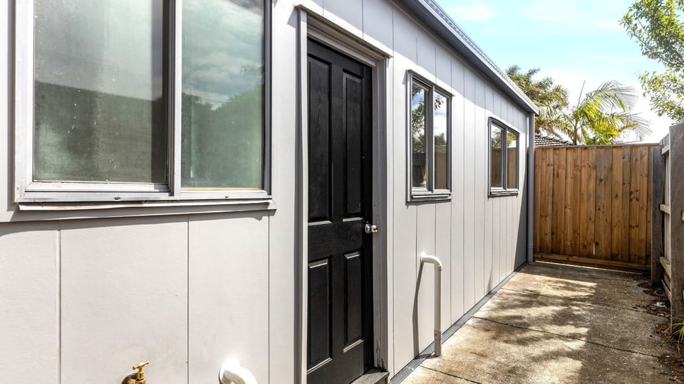 A private, paved walkway runs alongside the sleek modern siding of the coastal villa.