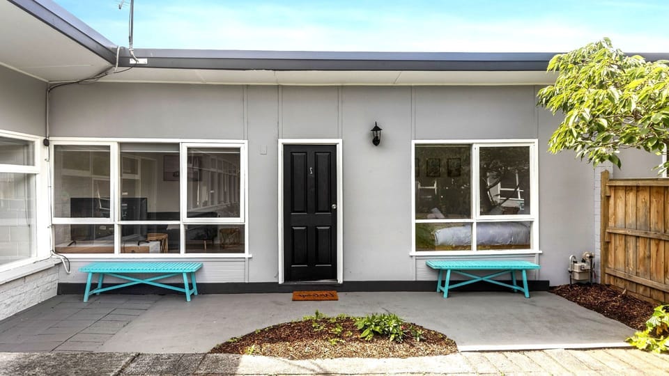 Two charming turquoise benches add a lovely splash of color to the property's clean, welcoming exterior entryway.