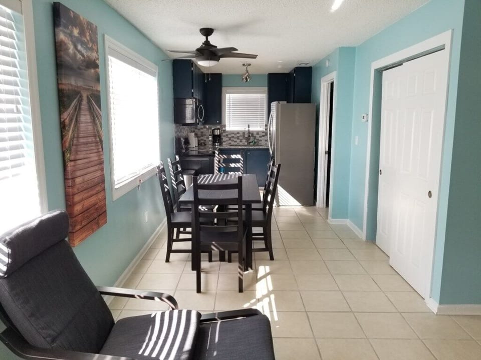 Bright dining area with modern decor, leading to a well-equipped kitchen.