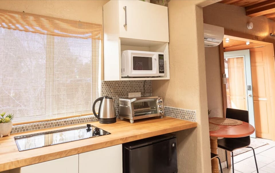 Whip up easy meals in this thoughtfully equipped kitchenette featuring a sleek cooktop, microwave, toaster oven, kettle, and mini fridge—perfect for light cooking during your stay.