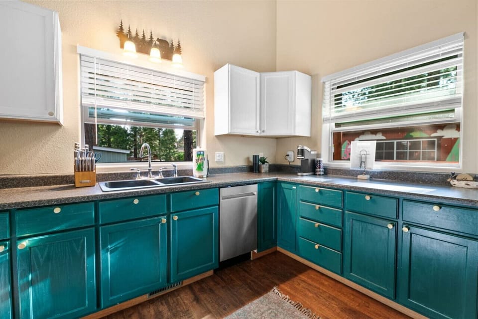 Corner kitchen view highlighting teal cabinets & natural light from nearby windows.