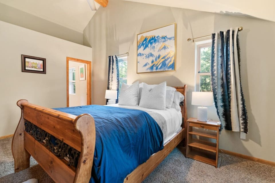 Cozy bedroom w/ wood bed frame, blue bedding, & simple decor for restful nights.