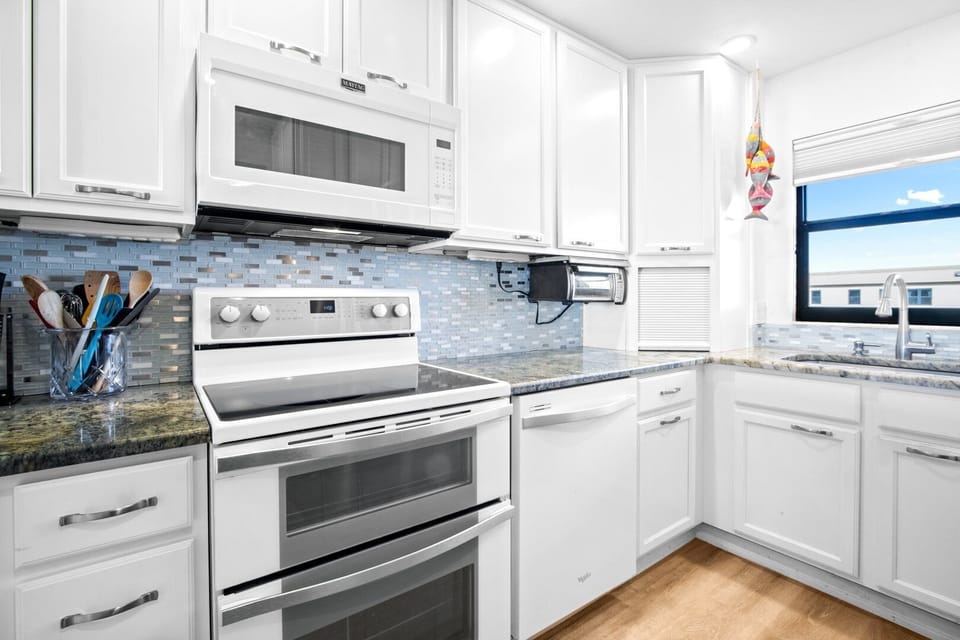 Modern kitchen fully equipped with sleek appliances and stylish backsplash.
