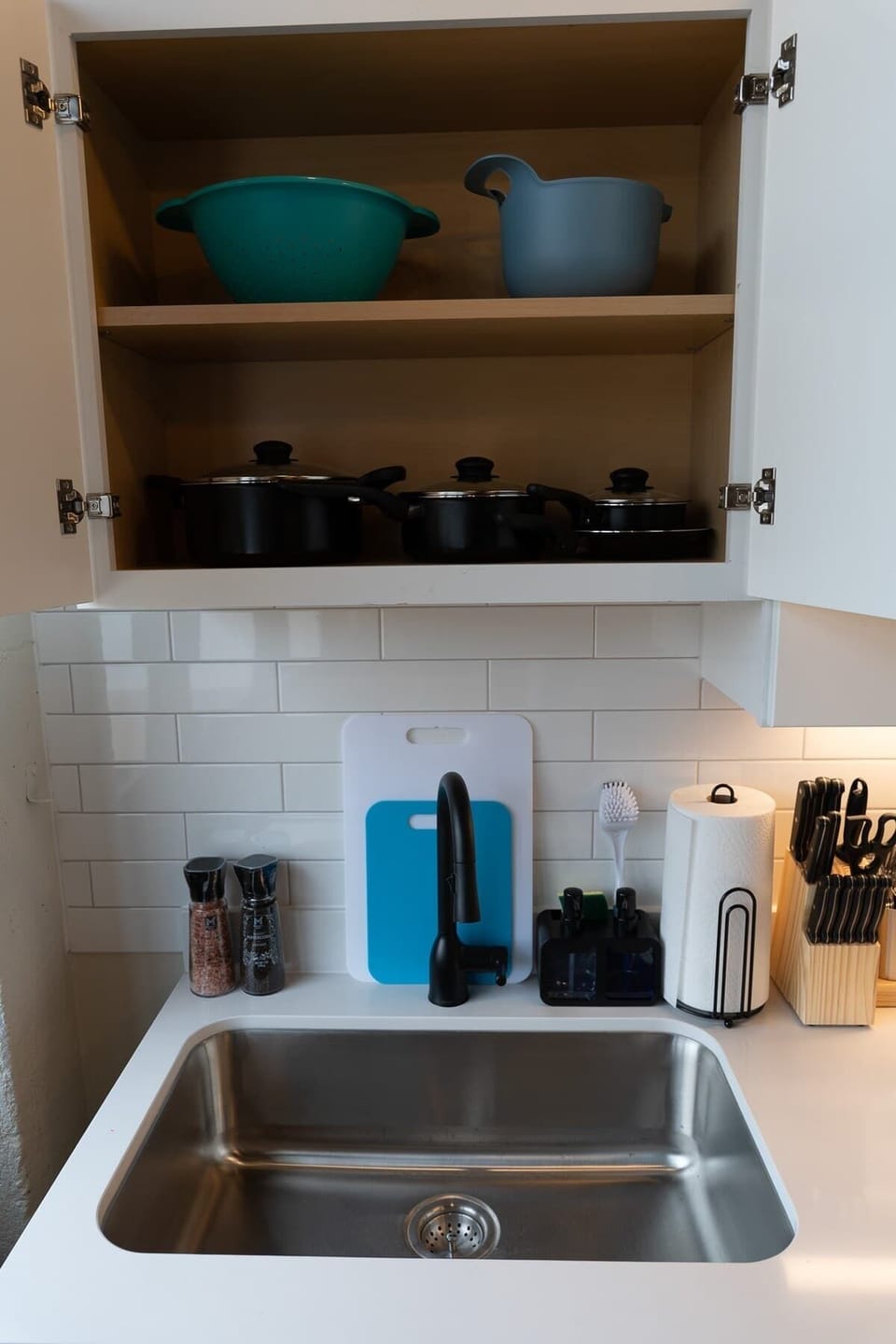 Sink area with upper cabinet and kitchen essentials