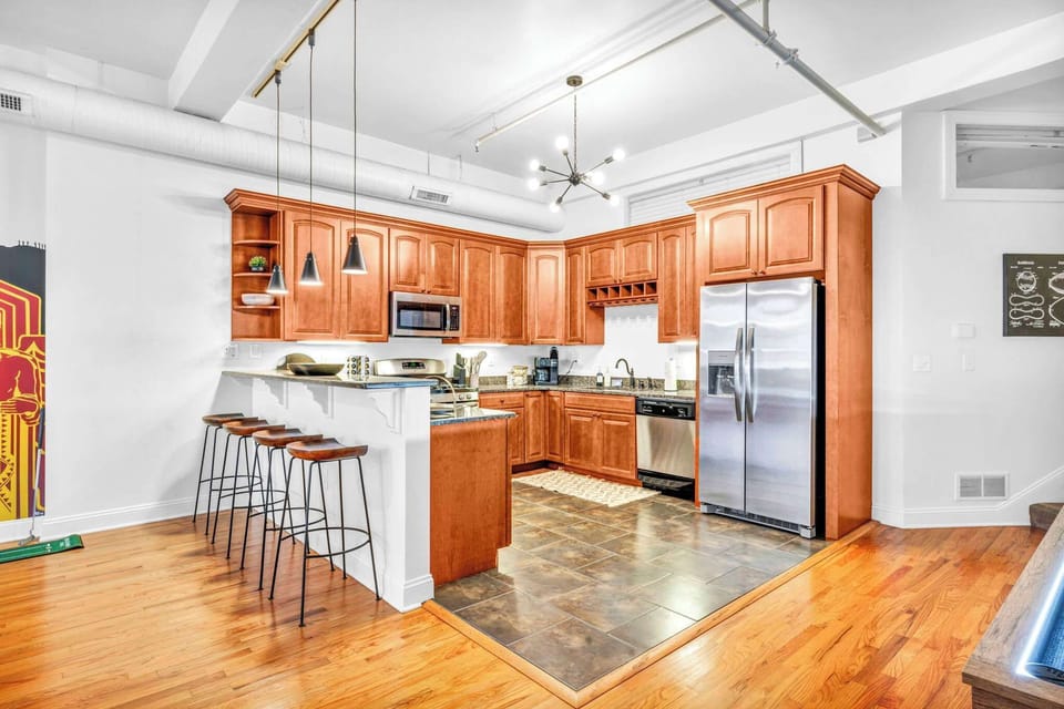 The property showcases a stunning kitchen wrapped in warm brown and crisp white tones, elevated by a statement chandelier that adds a touch of elegance, with essentials beautifully organized for a seamless and luxurious cooking experience.