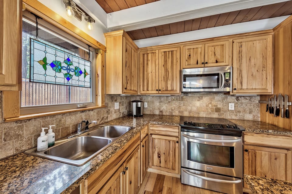 Cook in your fully equipped kitchen featuring warm wood cabinets, granite counters, and charming stained glass window views.