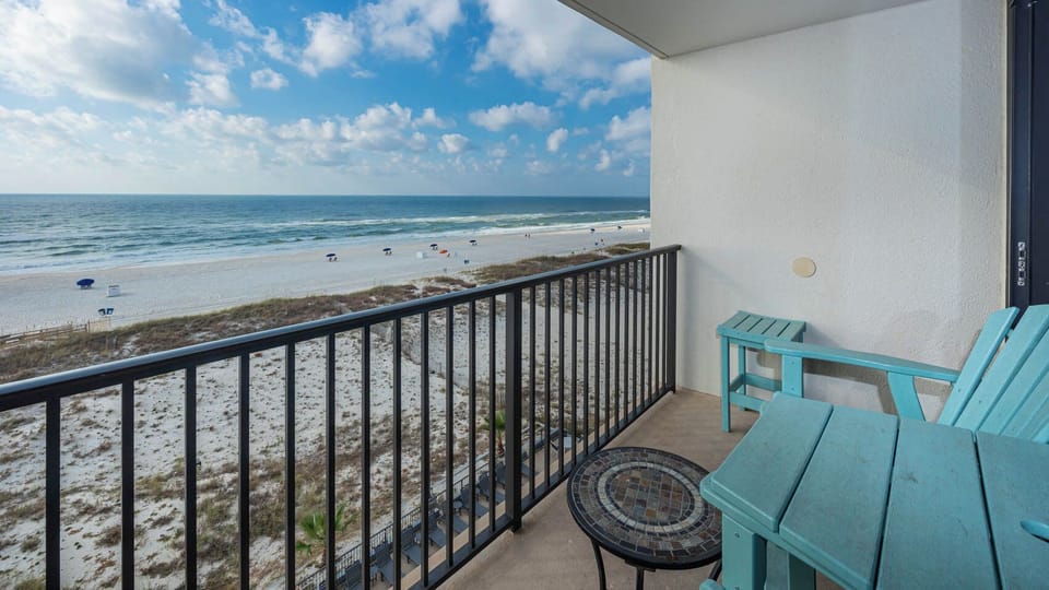 Enjoy breathtaking beachfront views from this balcony, featuring comfortable turquoise seating and a stylish mosaic table