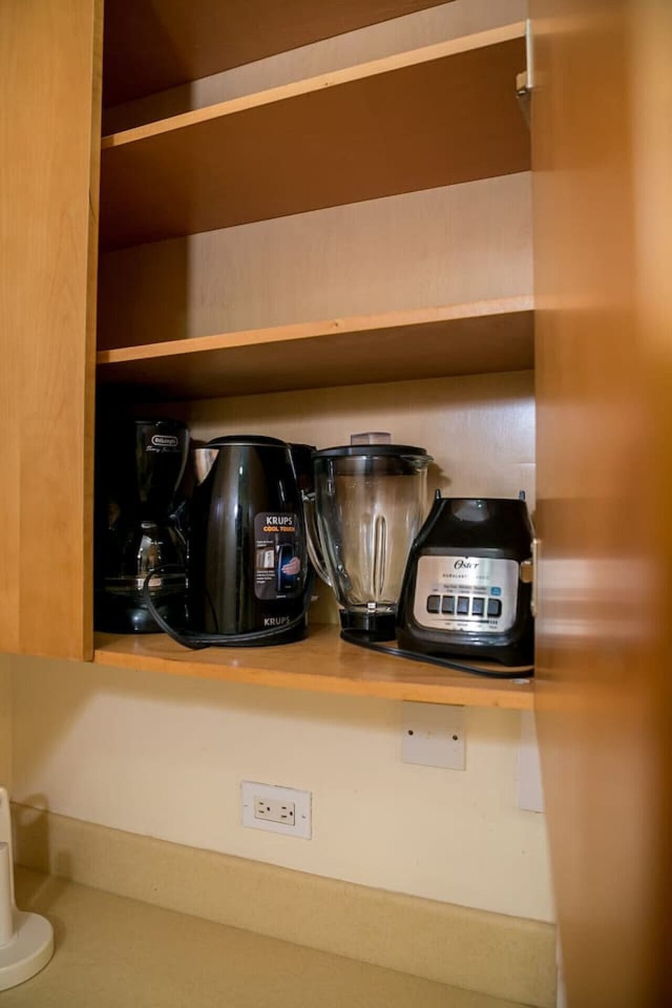 Kitchen shelf stocked w/ blender, kettle & appliances for convenient meal prep.