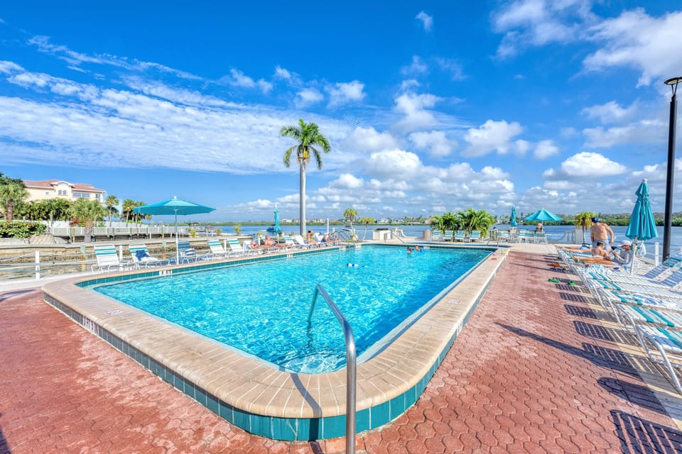 Pool with chaise loungers on pool deck next to the bay.