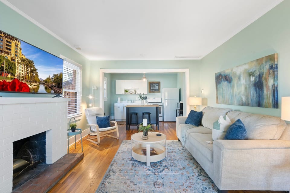 Fireplace-front seating with warm wood floors and layered textiles—stretch out on the sofa, gather around the coffee table, and enjoy the airy feel from all the windows and soft curtains.