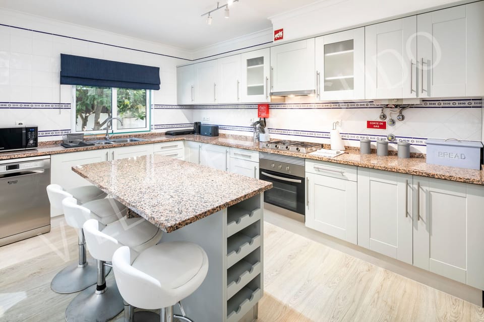 Modern kitchen in Villa Ferragudo with granite island and garden view.