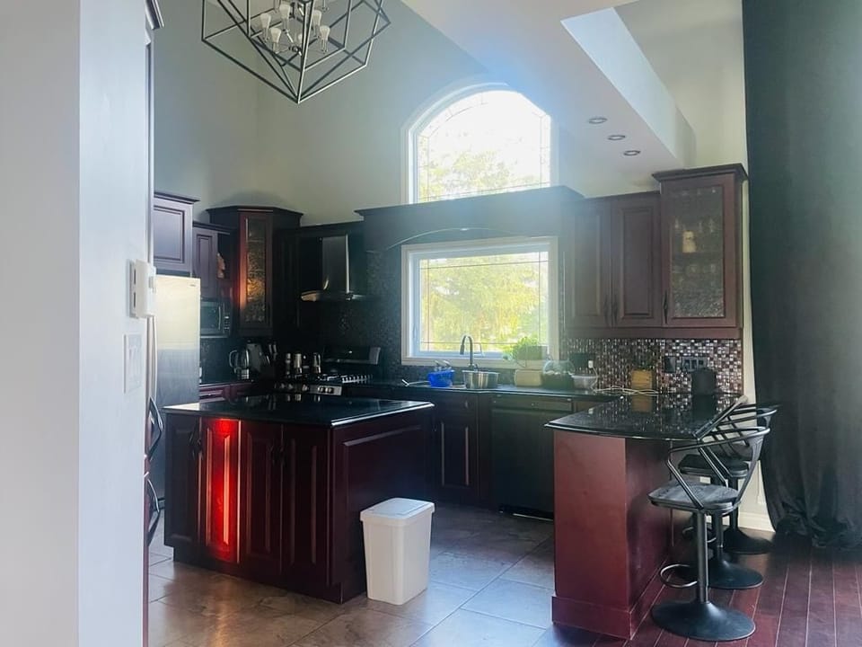 Full kitchen with fridge and gas stove, bar with 3 bar stools