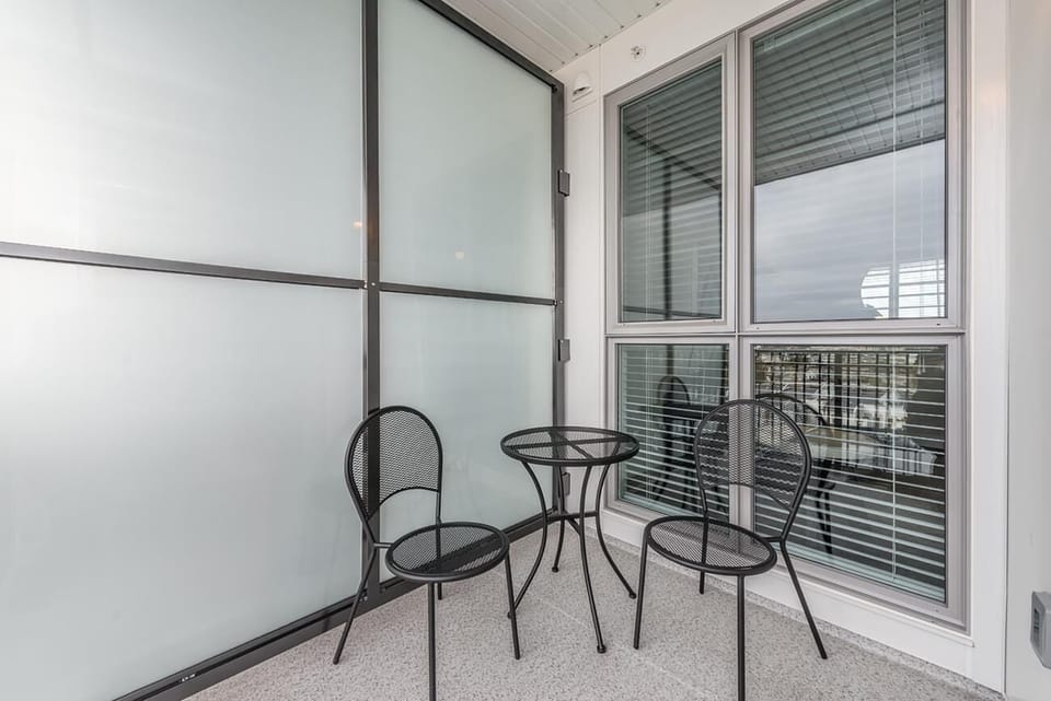 Private covered outdoor balcony complete with compact table seating and protective glass paneling.