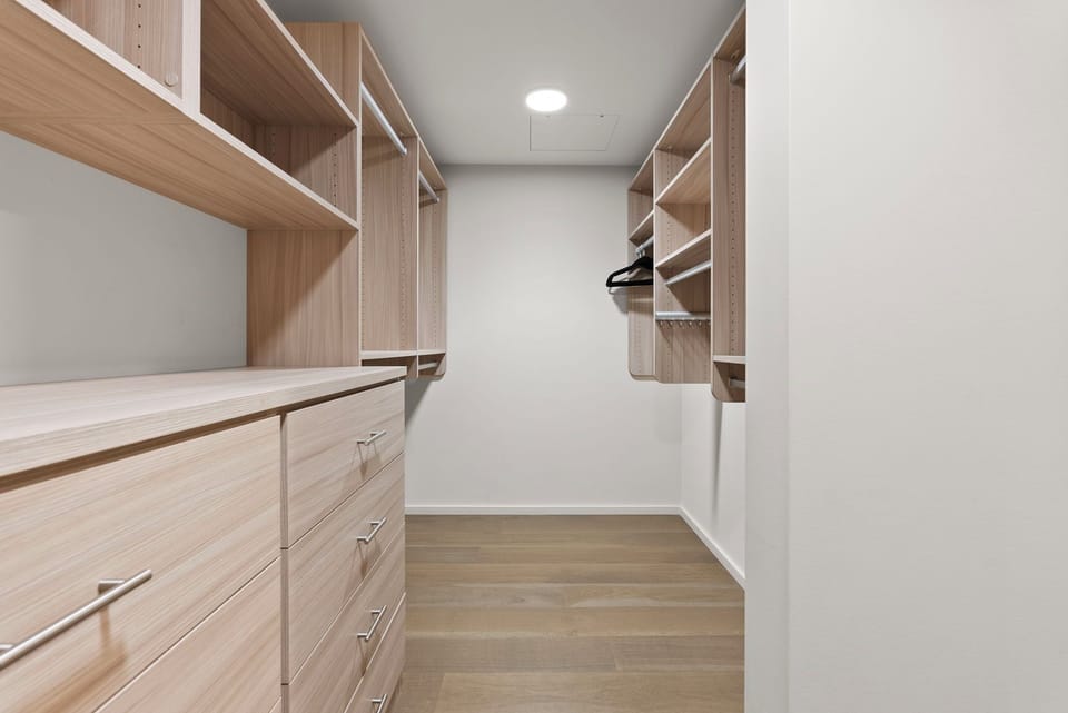 Another view of the walk-in closet, featuring built-in shelves and hanging space for all your belongings.