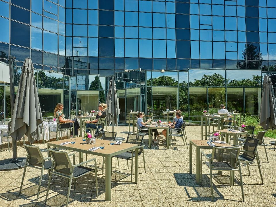 Soak up the sun and enjoy a leisurely moment on this outdoor terrace, perfect for unwinding with views of lush greenery and modern architecture.