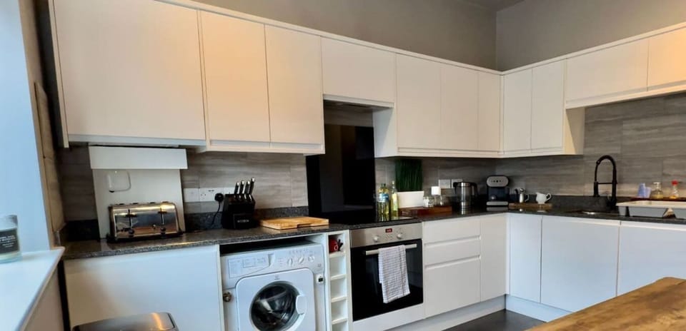 Contemporary kitchen designed for comfort and convenience. The space includes quality appliances, a washing machine for laundry, spacious work surfaces, and thoughtful storage—ideal for preparing meals and handling household tasks.