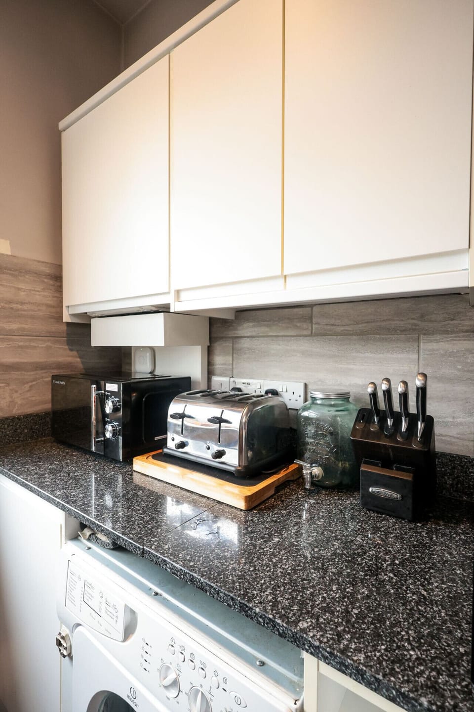Contemporary kitchen designed for comfort and convenience. The space includes quality appliances, a washing machine for laundry, spacious work surfaces, and thoughtful storage—ideal for preparing meals and handling household tasks.