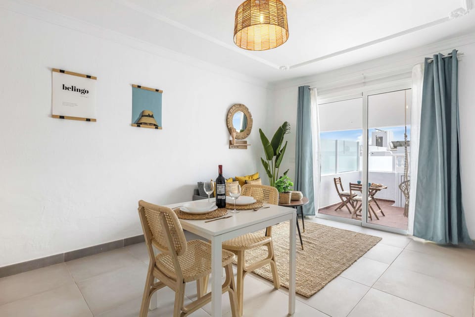 Acogedor y luminoso salón comedor con decoración natural y terraza privada, ideal para relajarse y disfrutar de momentos únicos. 🌿🍷 Descubre el confort de Palm Sunset y reserva tu estancia hoy.
