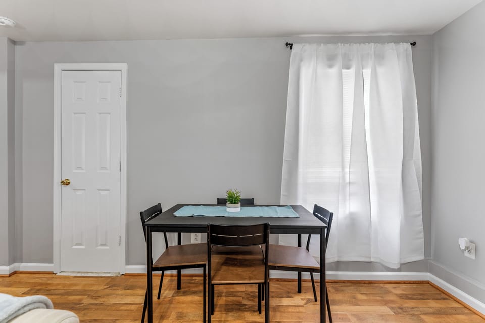 Minimalist dining room with a table, four chairs, and a touch of greenery.