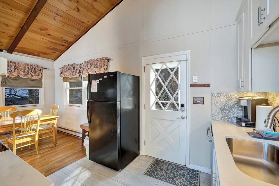 Enjoy shared meals and casual chats in this bright kitchen-dining area, featuring sleek appliances, a bold black fridge, and a table ready for your favorite moments.