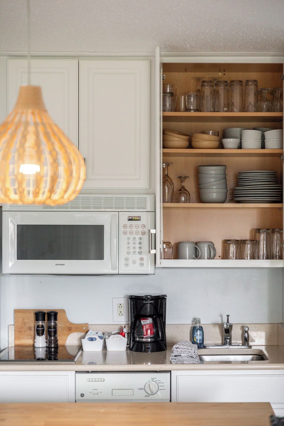 Kitchen details w/ open shelving, microwave & warm lighting accents.