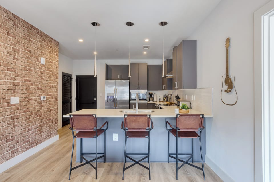 Kitchen features barstool seating and stainless steel appliances.