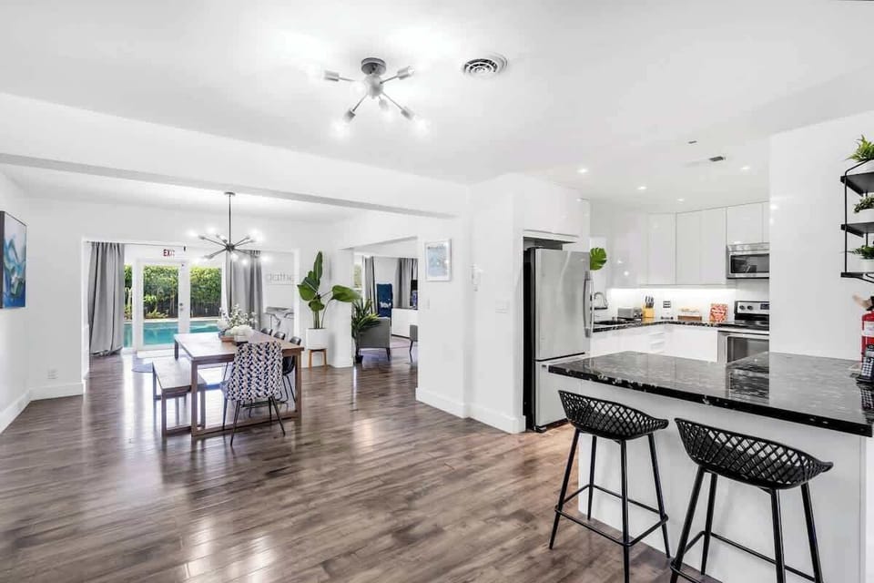 "Indoor elegance meets outdoor bliss—this Airbnb features a sleek kitchen, cozy lounge, and poolside views through glass doors."