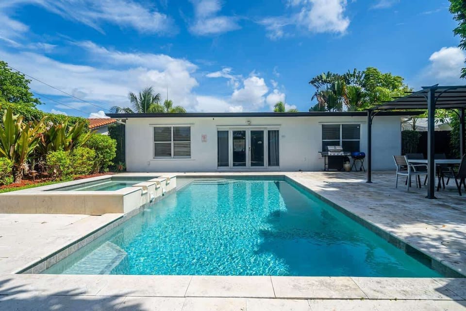 "Grill, chill, and soak it all in—this Airbnb backyard oasis features a pool, hot tub, shaded dining, and tropical vibes for unforgettable outdoor living."