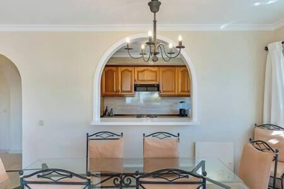 Elegant dining area with a beautiful glass table for six, cushioned chairs, and warm lighting. (6)