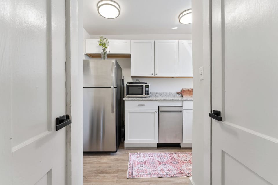 Modern kitchen with white cabinets, granite, stainless steel, and ample space.