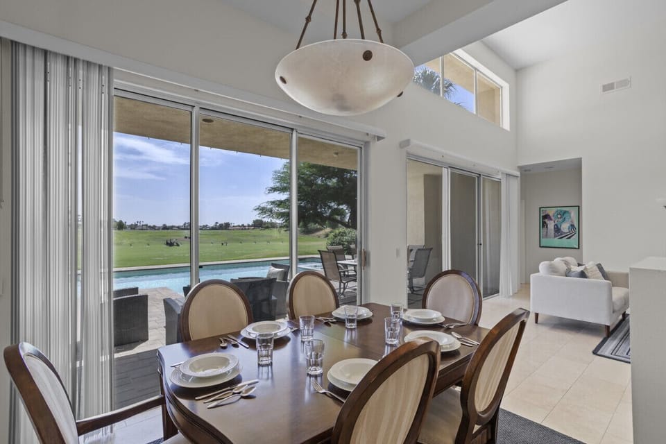 Bright dining area w/ large windows & views of the pool and golf course beyond