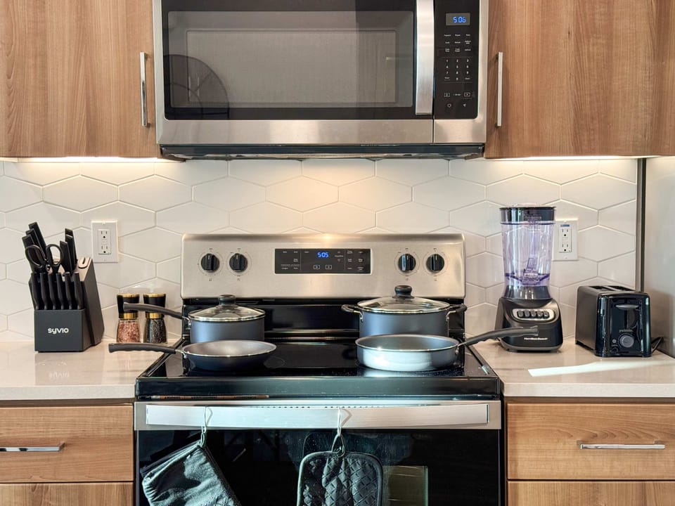 Modern kitchen amenities for extended stays: stovetop, fridge, dishwasher, microwave, kettle, toaster, blender, and a full knife set.