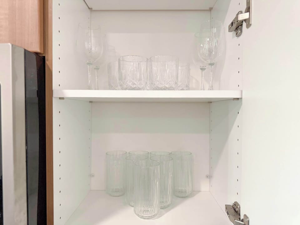 Fully equipped kitchen ideal for extended stays, featuring a complete set of glasses, mugs, wine glasses, plates, and bowls.