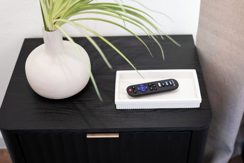 Chic nightstand décor with a modern vase and TV remote for a touch of comfort.