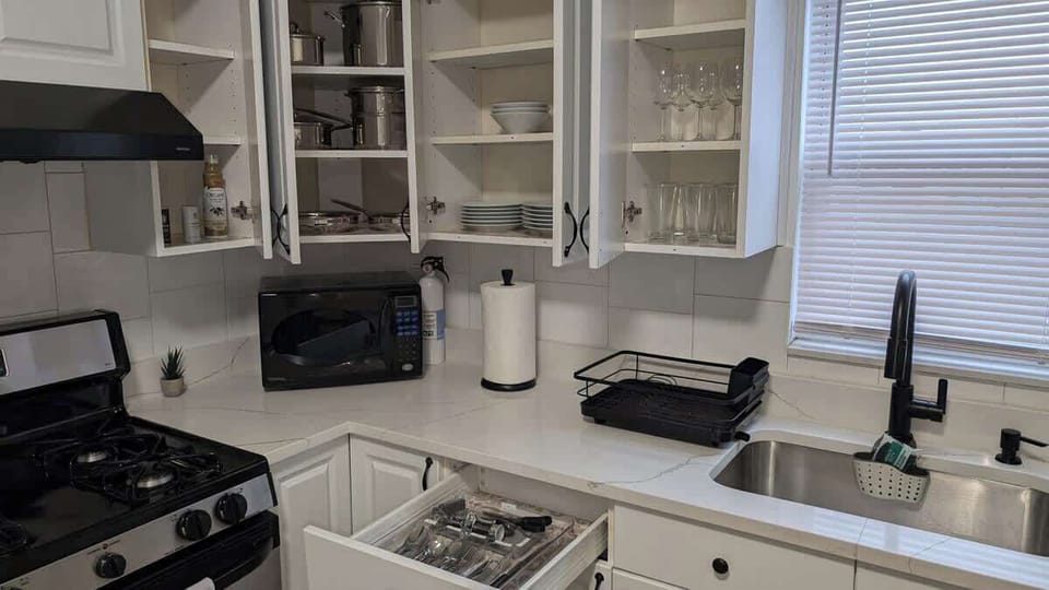 Fully equipped kitchen featuring modern appliances, including a gas stove, microwave, hot water kettle, and coffee maker, along with neatly organized drawers stocked with silverware and essentials—perfect for cooking your favorite meals
