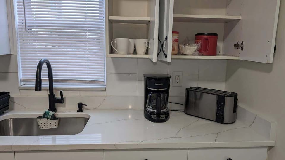 Fully equipped kitchen featuring modern appliances, including a gas stove, microwave, hot water kettle, and coffee maker, along with neatly organized drawers stocked with silverware and essentials—perfect for cooking your favorite meals