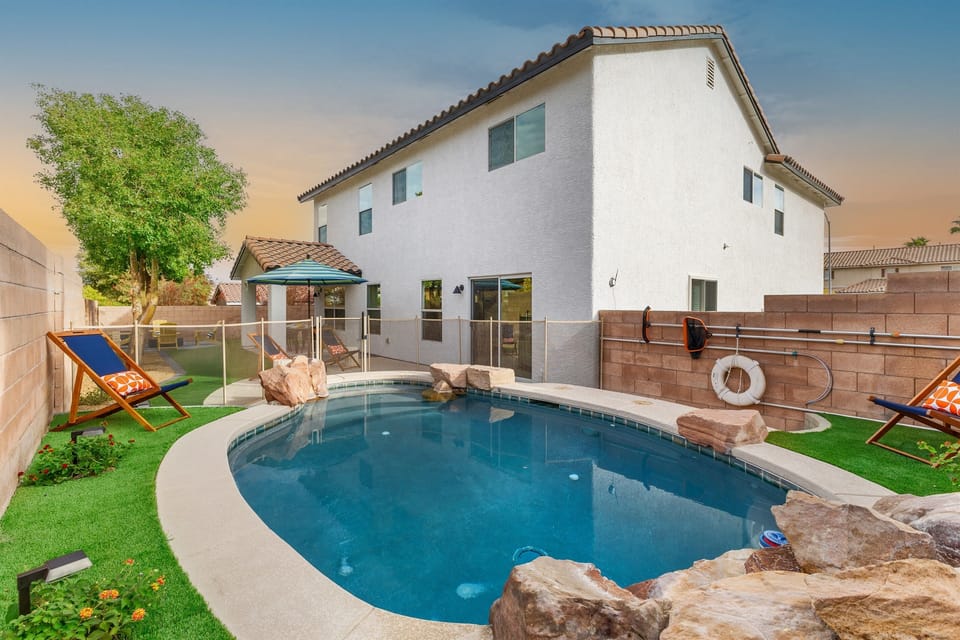 Our heated plunge pool with rock features and a waterwall is perfect in winter or summer.  Fenced off for the safety of your children.  Our covered patio and firepit can be seen beyond. -Adventure Awaits