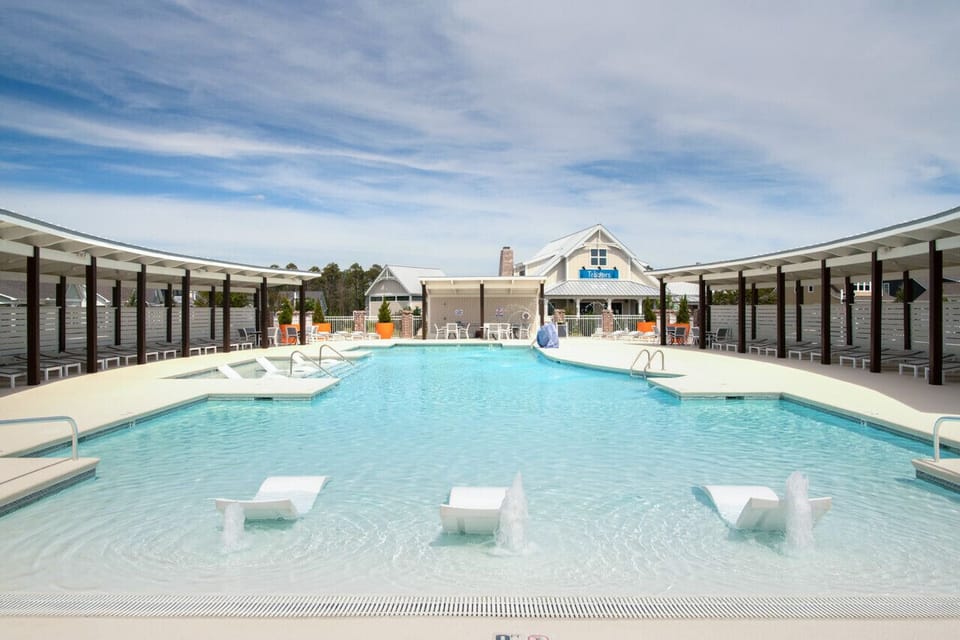 Sparkling community pool with shallow lounge area and shaded seating