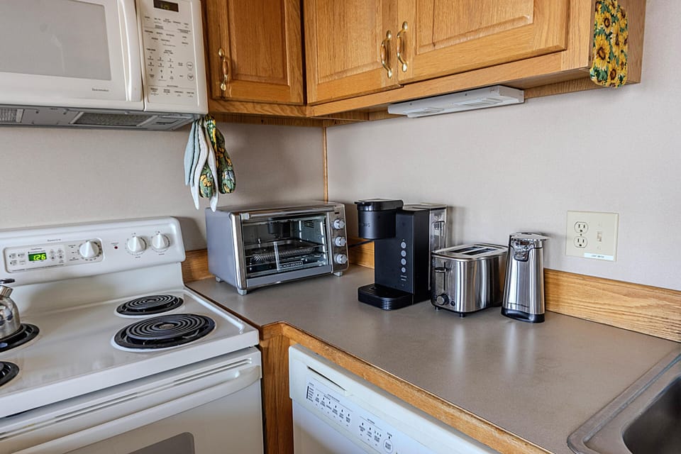A toaster oven, Keurig coffee maker, drip-style coffee maker (not shown), toaster, and a blender are some of the items in the fully-stocked kitchen.