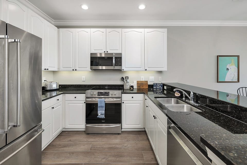 The fully-equipped kitchen features stainless steel appliances & granite counter