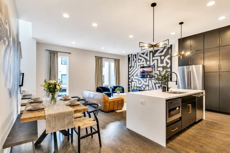 Open-concept flow from dining table to kitchen island keeps everyone in the same room for meals and morning coffee, all on dark hardwood floors