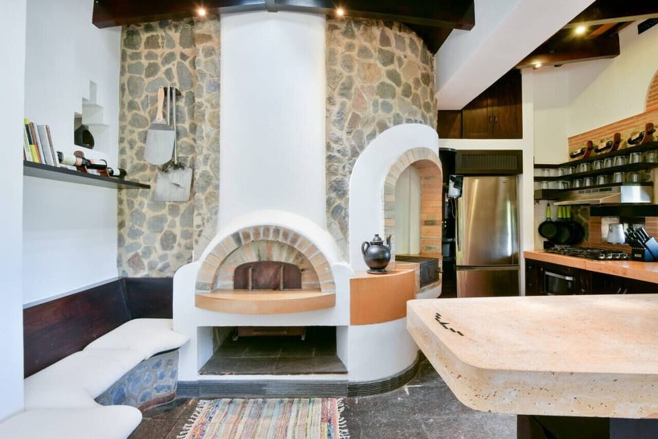 Main entrance view with interior wood-burning oven, wood burning grill, and kitchen.