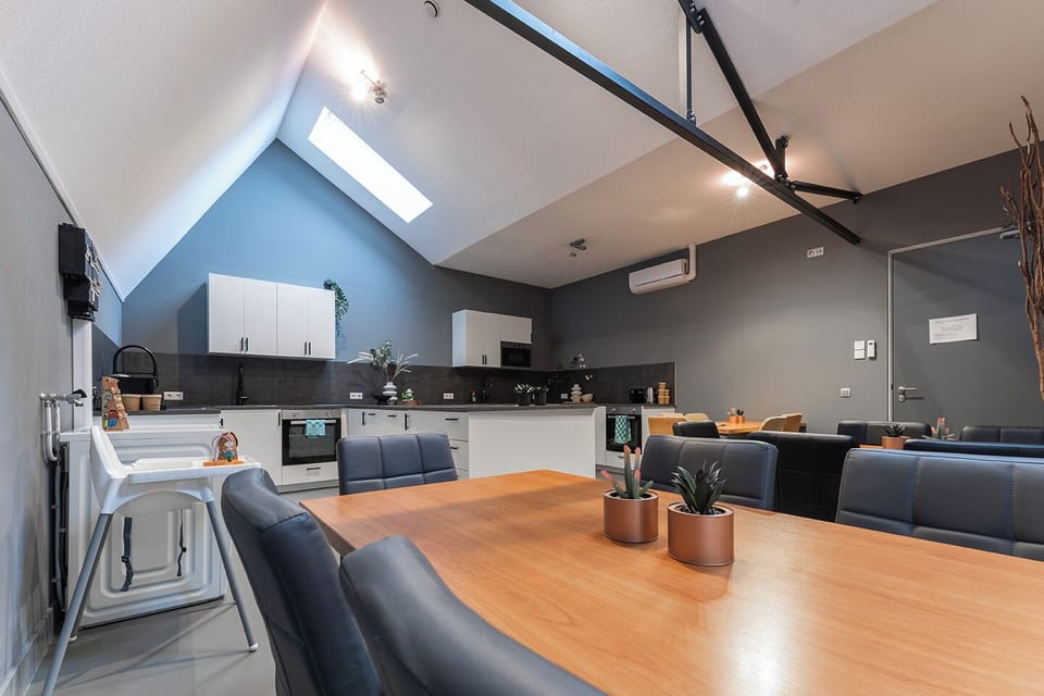 A bright, modern kitchen featuring sleek white cabinetry and dark countertops, all set beneath an eye-catching angular ceiling with skylights that flood the space with natural light.