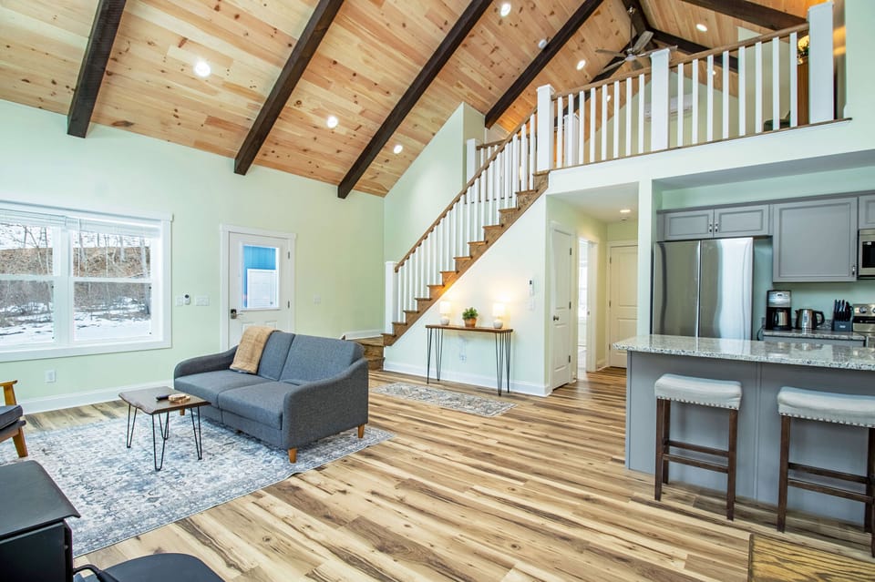 Living area with couch, television, wood stove, and expansive windows