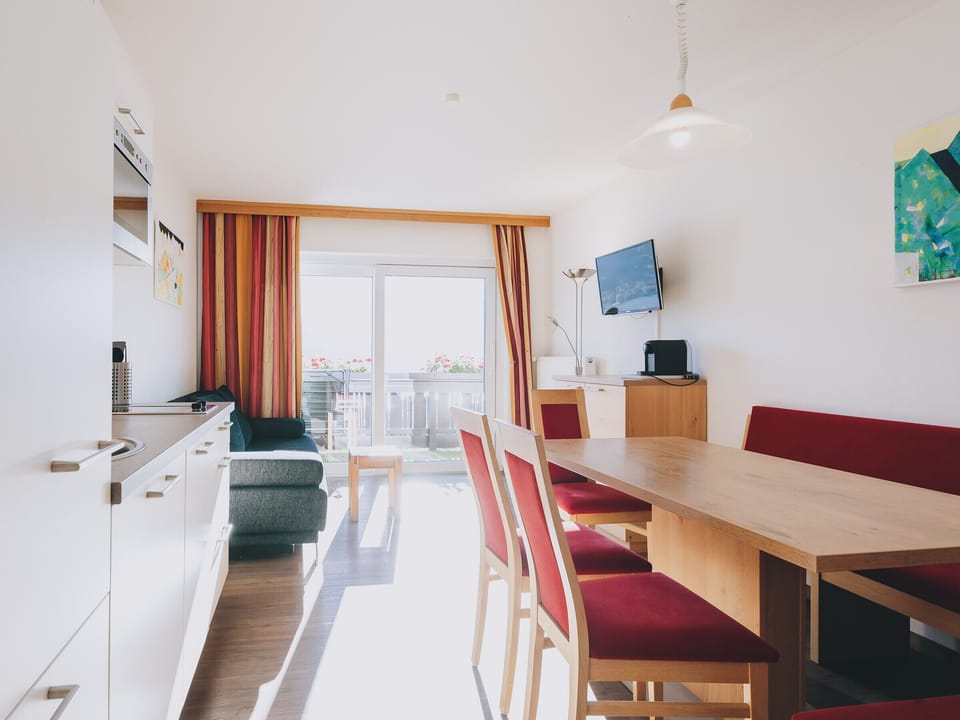 Dining room in the Apartments Haus Altenberger by we rent, with a table, chairs, and a kitchen equipped with a stove, oven, TV and Balcony.