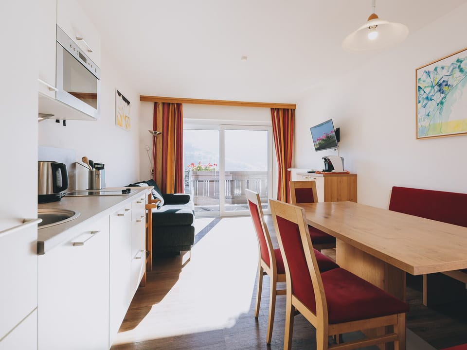 Dining room in the Apartments Haus Altenberger by we rent, with a table, chairs, and a kitchen equipped with a stove, oven, TV and Balcony.