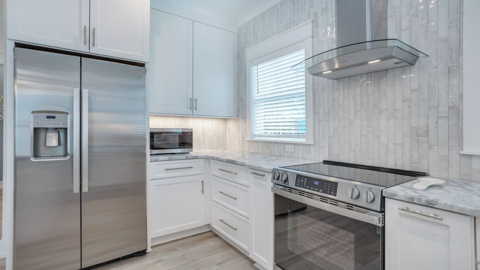 Crisp white cabinetry, marble countertops, and tile backsplash create a bright, polished look.